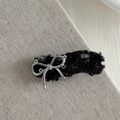 Detail einer Denim-Haarspange mit Silberschleife und Fransen auf grauem Hintergrund - Schwarz-Welle