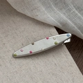 Close-up of silver metal hair clip with colorful enamel polka dots on linen background - One-line Shape with Colorful Dots