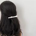 Pince à cheveux élégante avec double nœud blanc portée sur des cheveux bouclés foncés - Blanc