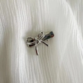 Close-up van een mini zilveren strik haarspeld met gladde metalen afwerking en grip - Eendenbek haarclips / Zilveren Strik