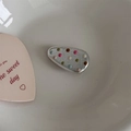 Detailed close-up of a silver hair clip with colorful 3D dots in a white ceramic dish - Silver Triangle Buckle