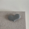 Dettaglio di un fermaglio per capelli a cuore grigio lucido su un tessuto con texture - Fermaglio a Cuore Grigio