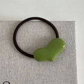 Detailaufnahme der grünen herzförmigen Haarspange mit glänzender Oberfläche und schwarzem Gummiband - Grün Herz Haargummi
