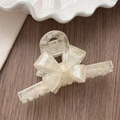 Detail showing the glossy acetate bow hair claw clip with iridescent finish and brand logo - Clear White