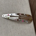 Gros plan détaillé de barrettes en métal à pois colorés sur un tissu texturé - Argent avec pois colorés Pince goutte d'eau