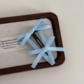 Détail de deux barrettes nœud en satin bleu clair avec base de clip BB noire sur bois - Bleu (Clip à Ressort Double Nœud)