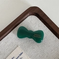 Macro detail of emerald green acetate bow clip with gold France Handmade lettering - Dark Green