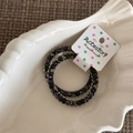 Close-up of two-piece beaded elastic hair ties with butterfly patterns on a white tray - Fine Style / Black
