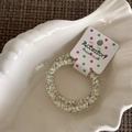 Macro view of spiral hair ring with floral pattern on a shell porcelain dish - Fine Style / Beige