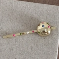Macro shot of gold metal hair clip featuring colorful polka dots and a spherical detail - Round Shiny Gold Bobby Pin
