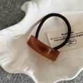 Macro shot of an amber resin hair tie buckle on a vintage white decorative plate - Brown