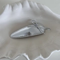 Detail shot of silver metallic leather bow hair clip with fine stitching on white plate - Stitched Silver Leather Waterdrop Shape