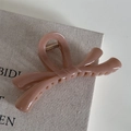 Gros plan d'une pince à cheveux rose en forme de nœud sur un tissu en lin - Nœud Croisé Gelée - Café