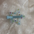 Detailed macro view of light blue star hair clip with colorful polka dots on lace fabric - Blue