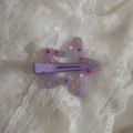 Close-up of a purple star hair clip with colorful polka dots on white lace background - Purple