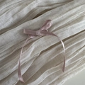 Detalle de diadema rosa con lazo de seda sobre fondo de lino marfil mostrando textura - Rosa