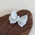 Dettaglio di un fermaglio per capelli a farfalla in acetato blu con logo SANSHINE - Azzurro