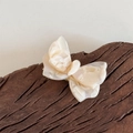 Dettaglio molletta a farfalla in acetato con trama perlescente e logo del marchio inciso - Albicocca Beige
