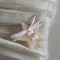 Macro detail of cream star hair clip with pink silk ribbon bow on textured soft fabric - Apricot Star