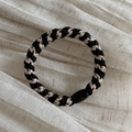 Close-up of woven hair tie with black and champagne gold fibers and smooth oval connector - Black and Beige