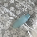 Close-up of a light blue matte duckbill hair clip on a white lace background - Blue