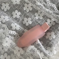 Macro view of a pink translucent matte hair clip resting on a white lace fabric background - Pink