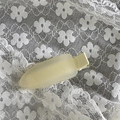 Détail d'une pince à cheveux mate jaune pâle sur dentelle blanche avec texture satinée - Blanc Cassé