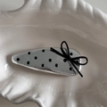 Close-up of silver polka dot hair clip with black bow detail in a white shell tray - Water Drop