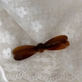 Vue détaillée de la barrette à cheveux nœud en écaille marron avec étiquette dorée - Café