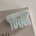 Macro detail of marble light blue acetate hair claw with golden Barrette La France text - Blue Marble