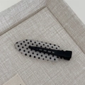 Detailed close-up of a resin polka dot duckbill hair clip on a soft textured fabric background - Clear Polka Dot - Seamless Clip