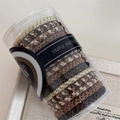 Detail of woven high-elasticity hair ties in brown and beige colors inside a clear tube - Gold Thread Coffee
