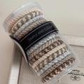 Detailed macro view of multi-colored braided elastic hair ties in a clear storage jar - Beige Apricot