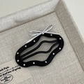 Primer plano de una pinza BB de lunares con lazo de cinta plateada sobre tela - Nube Negra