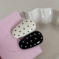 Close-up of black and white polka dot hair clips with glossy finish on pink card - Smooth Oval Shape