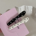 Close-up of black and white polka dot wave hair clips set on a decorative white plate - Wave Bar Clip