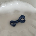 Detail of blue denim fabric bow hair clip featuring black trim and textured woven patterns - Acetate Denim Texture - Asymmetrical Bow