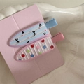 Detailed macro view of two cute floral and polka dot hair clips on a display card - Sweet Pair - Blue Pink