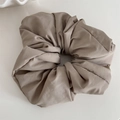 Close-up of oversized pleated taupe scrunchie with matte fabric texture and soft folds - Light Coffee