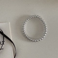 Dettaglio ravvicinato di un elastico per capelli a spirale argento su sfondo grigio - Argento Stile Sottile