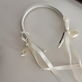 Detailed close-up of cream-white satin bow headband with elegant long trailing ribbons - Bow Streamer Style / White