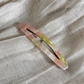 Dettaglio del fermaglio in acetato con trama ambra rosa su tessuto di lino beige - Verde e Rosa