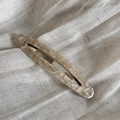Dettaglio ravvicinato di un fermaglio per capelli in acetato marmorizzato su tessuto di lino - Albicocca Beige