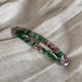 Dettaglio del fermaglio per capelli in acetato marmorizzato su tessuto beige strutturato - Verde
