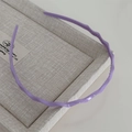 Détail d'un serre-tête ondulé violet sur une boîte beige avec une finition brillante - Violet
