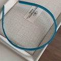 Detailed view of teal acetate headband with anti-slip inner teeth on a textured gray base - Mint Blue
