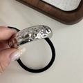 Detalle de un adorno de metal plateado texturizado en un coletero negro elástico - Cuerda de Pelo Martillada de una Capa-Plateado