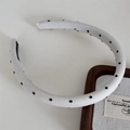 Detailed view of a white fabric headband with classic black polka dots on wooden tray - Narrow Polka Dot / White