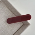 Dettaglio di un fermaglio per capelli in resina bordeaux lucida su un vassoio intrecciato - Fermaglio a Barra Pasta di Fagioli