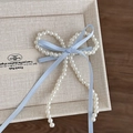 Dettaglio dell'elegante fermaglio per capelli in perle con nastri azzurri e nappe - Fermaglio Perla Blu con Nastro